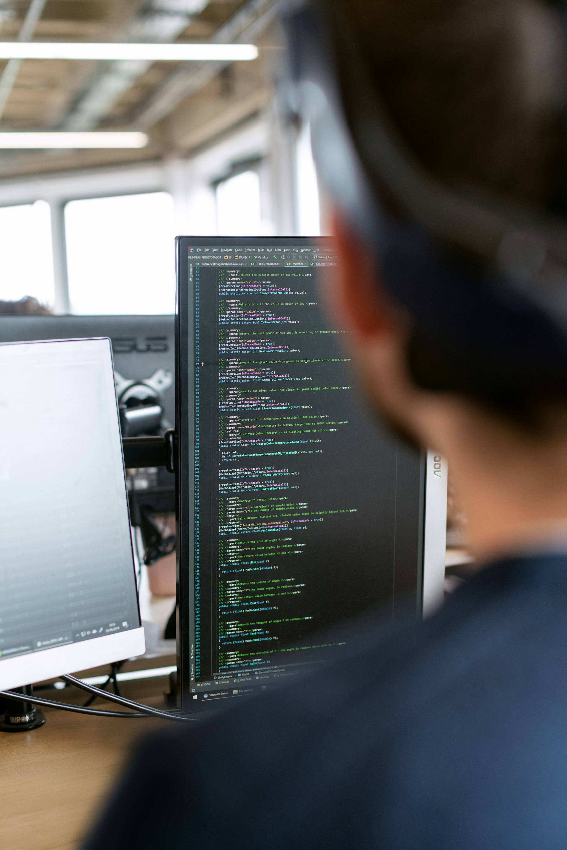 Software engineer writing code on multiple monitors